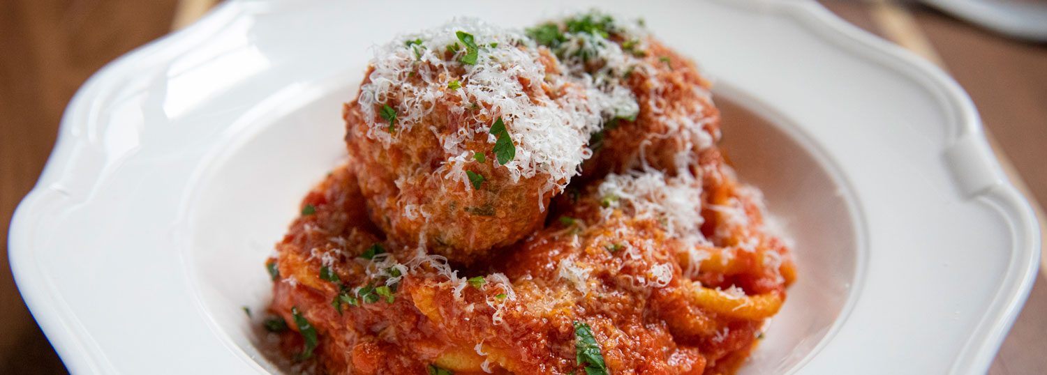 Spaghetti and meatballs topped with tomato sauce and freshly grated cheese
